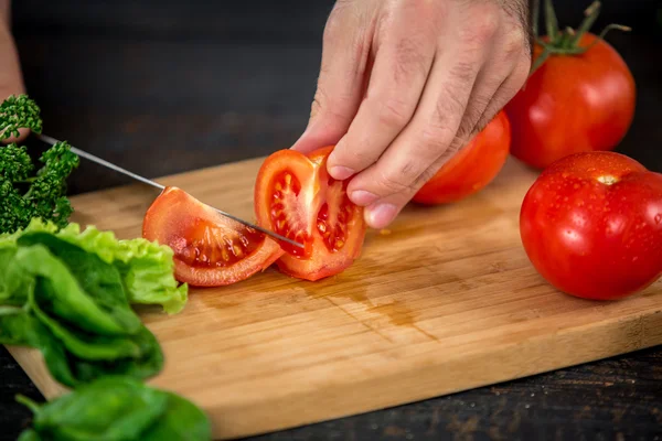 Male hands cutting vegetables for salad