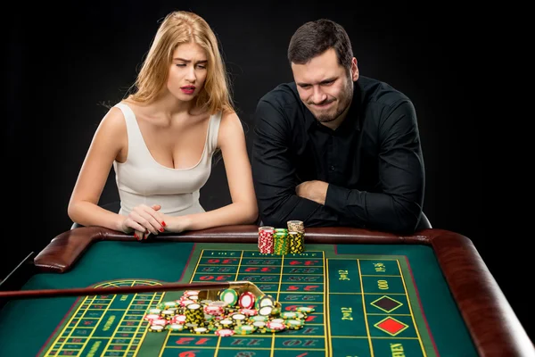 Men with women playing roulette at the casino.