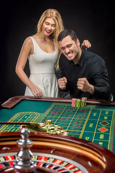 Young couple celebrating win at roulette table in casino.