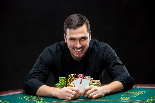 Happy poker player winning and holding a pair of aces