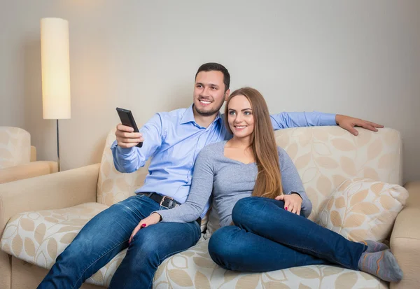 Portrait of happy couple sitting on sofa watching television together