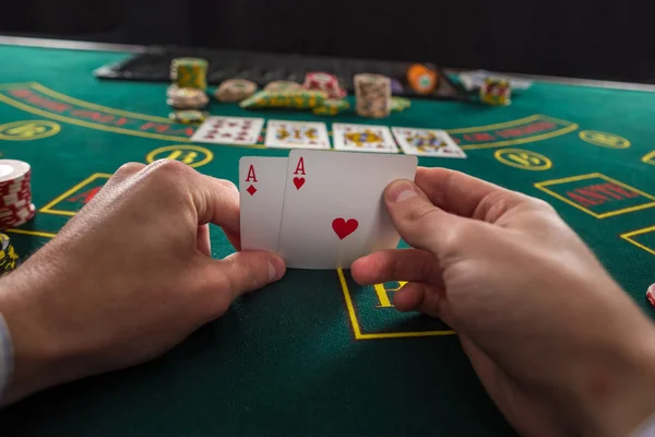 Male poker player lifting the corners of two cards aces