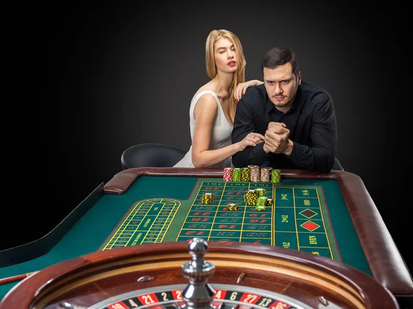 Men with women playing roulette at the casino.