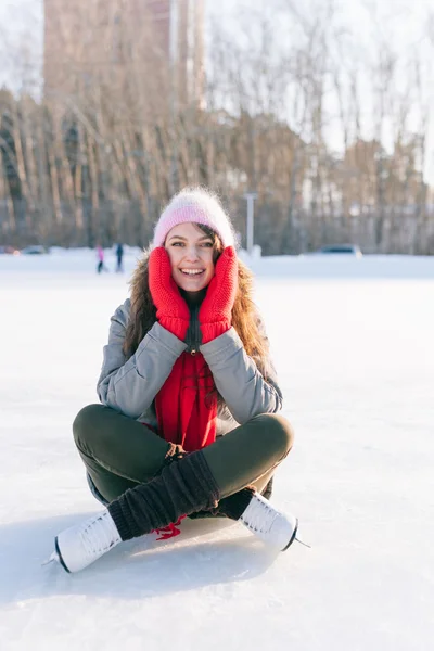 Ice skating woman sitting on the ice smiling