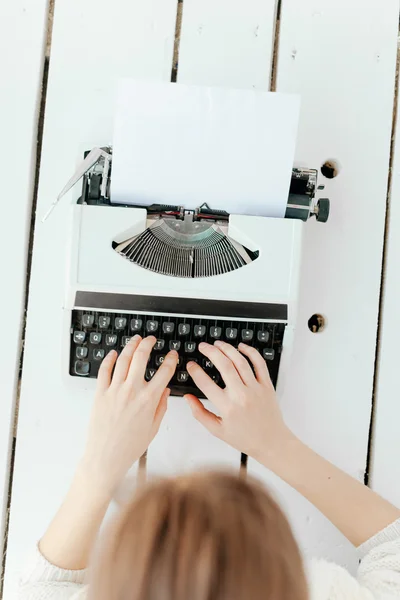 Womans hand typing on retro machine