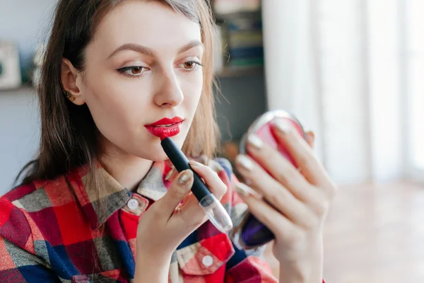 Beautiful pin-up girl applying red lipstick