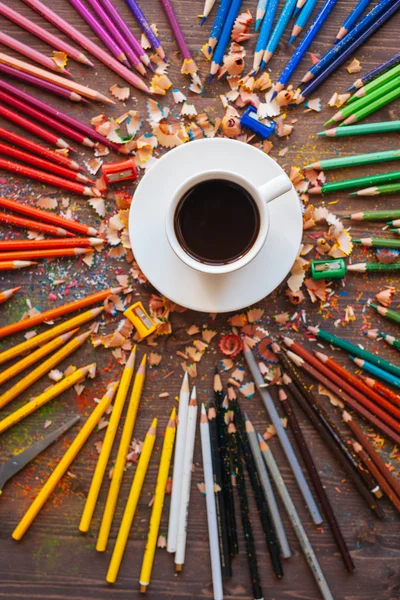 Color pencil and a cup of coffee on wooden background