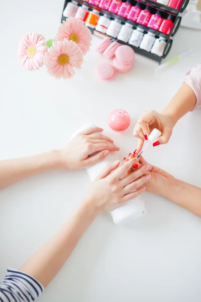 Woman in salon receiving manicure by nail beautician