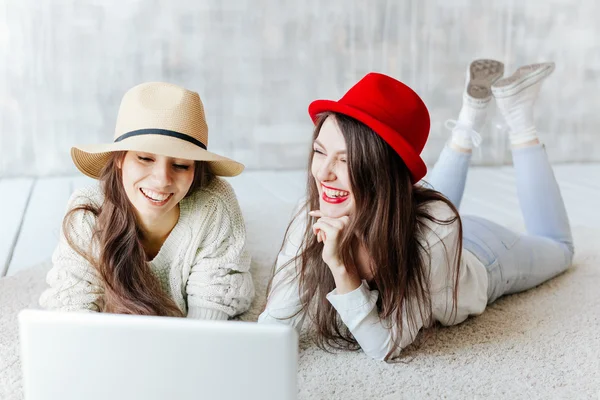Two Happy Women Looking At Laptop While Lying On Floor