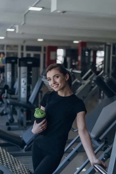 Beautiful girl holding a shaker in the gym