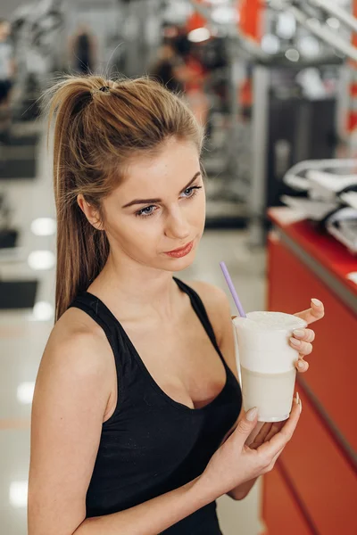 Beautiful blonde in the gym drink protein