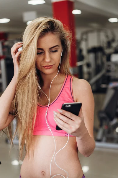 Blonde with a phone  at the gym. Listening to music