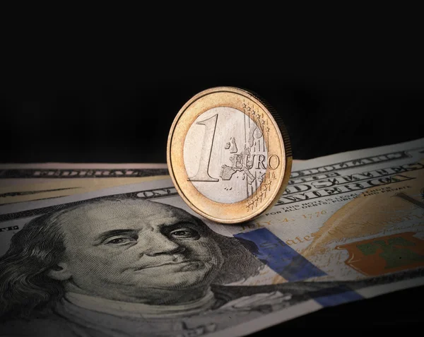 Money euro dollar coin on a hundred dollars banknote on a background