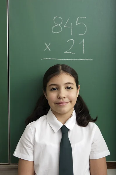 Little girl with example math on the blackboard