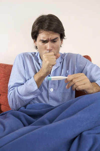 Sick man coughing and looking at thermometer