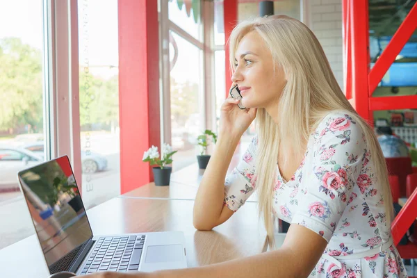 Girl works for a laptop and talking on the phone