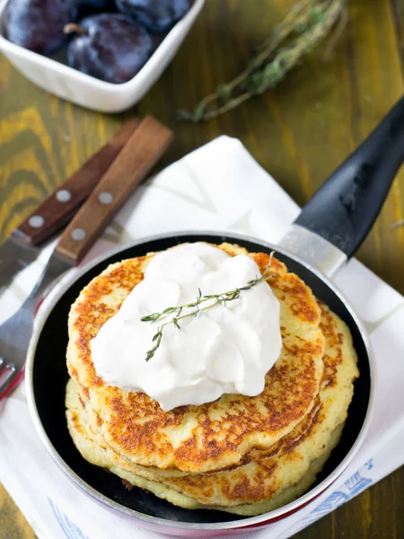 Potato pancakes in a pan with sour cream