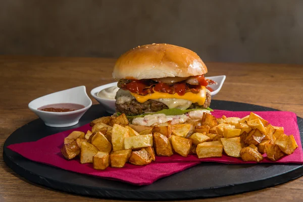Large burger served with crispy baked potatoes
