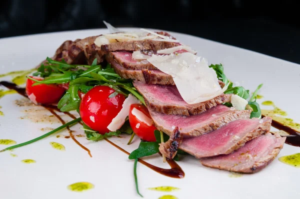 Medium rare steak served on a plate with vegetables and cheese