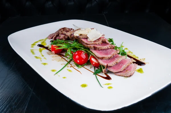 Medium rare steak served on a plate with vegetables and cheese