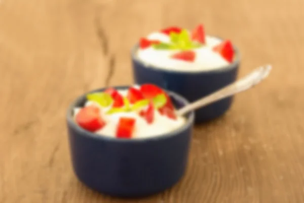 The blurred image for the background. Milk fruit dessert. Whipped cream with strawberries.  Blue cup with cream and a silver spoon. Berries and cream.