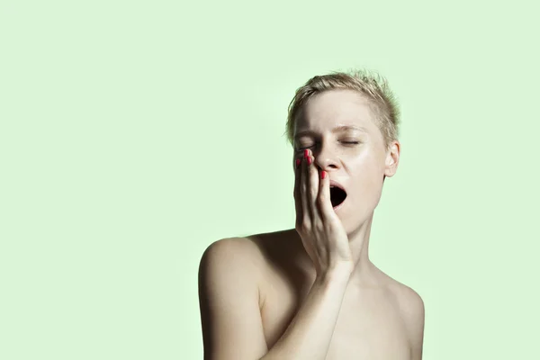 Portrait of white young woman yawn, short hair, face with freckles, green background