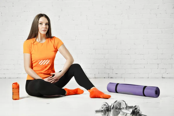 Sport fit woman posing in a gym with equipment, dumbbell and training pad