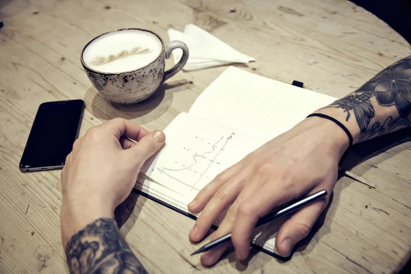 Close-up view of male hands with note book and coffee top view