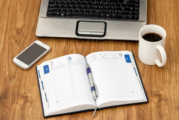 Office table with notebook, cup of coffee, notebook and smartphone