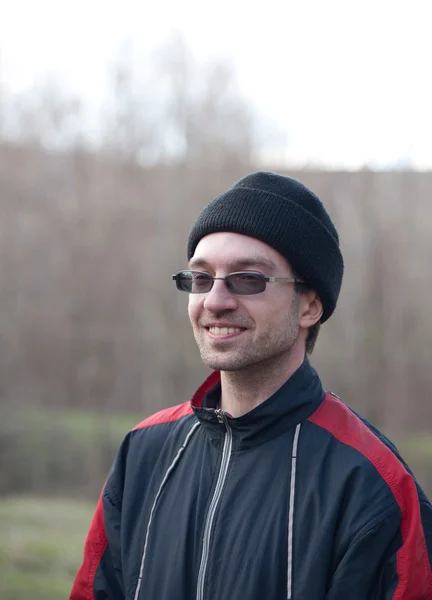 A guy in a sports jacket and glasses smiling