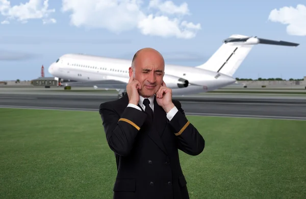 Airline employee covering his ears from the jet noise