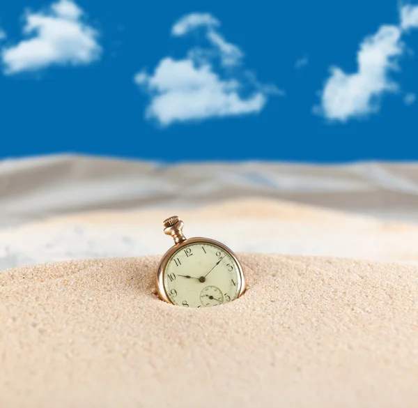 Vintage pocket watch semi buried in the sand