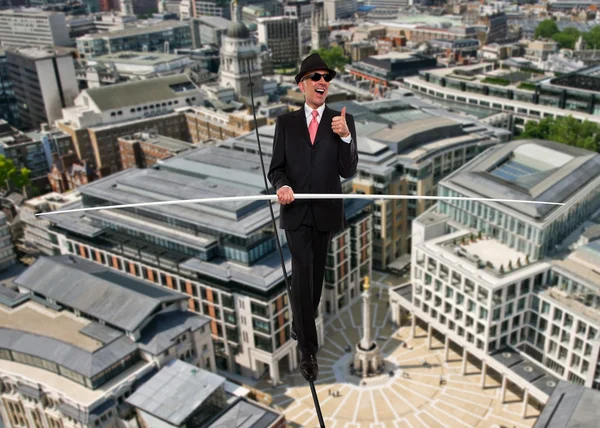 Business man in equilibrium on a rope over a city