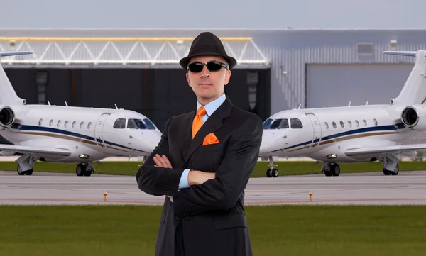 Handsome business man standing in front of private jets