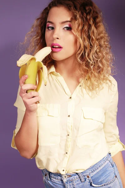 Beautiful young woman eating banana