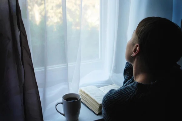 Coffee, book and girl looking out the window