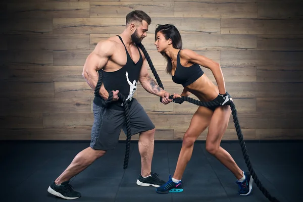 Muscular man with beard and beauty girl pulling a rope