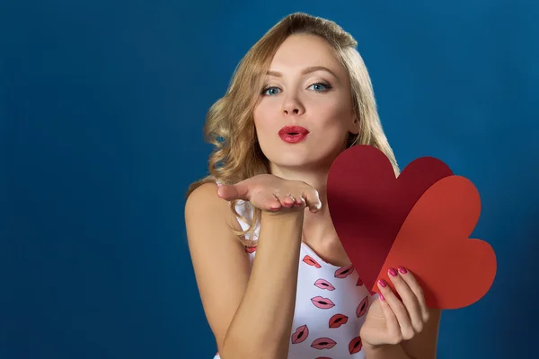 Blond woman holding two hearts air kiss red lips
