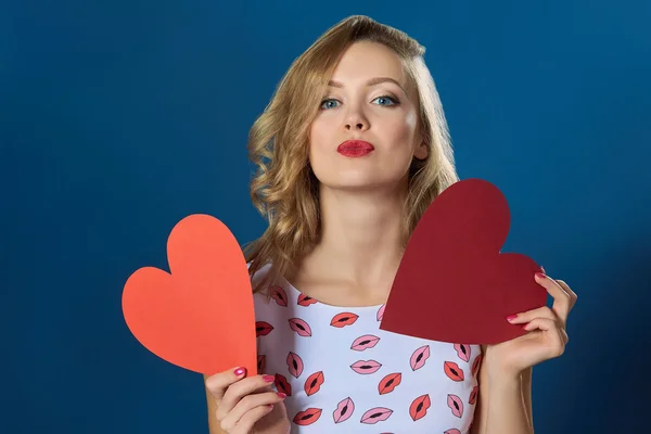 Blond woman holding two hearts kissing red lips