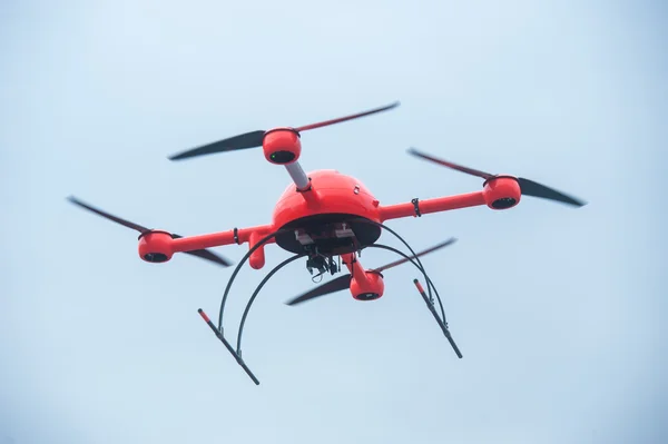 Red industrial drone flies over metal structures industrial faci