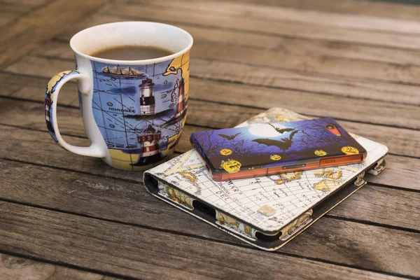 Tea mug, e-reader and mobil phone on a table