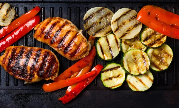 Barbecue grilled chicken and vegetables on cast iron table