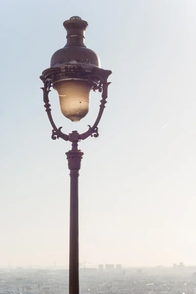 Vintage street lamp on Montmartre with morning foggy skyline of Paris in the distance