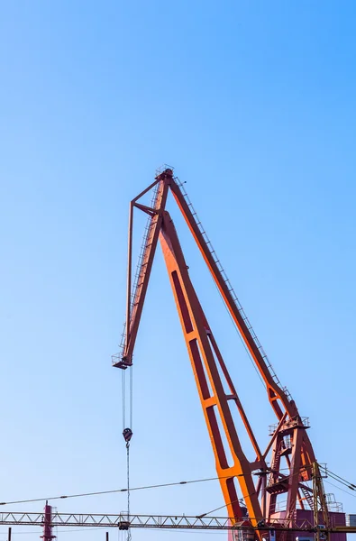 Red truck crane boom with hooks and scale weight above blue sky