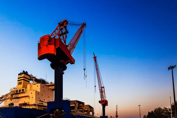 Red truck crane boom with hooks and scale weight above blue sky