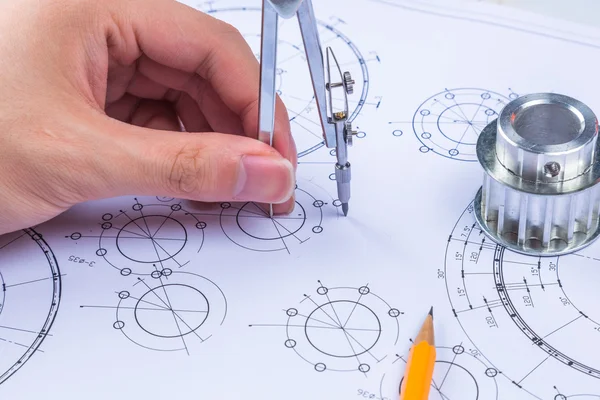Man\'s hand with a compass. Mechanical engineer at work. Technical drawings. Pencil, compass, calculator and hand man. Paper with technical drawings and diagrams.