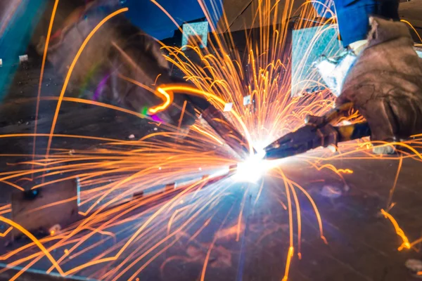 Sparks while welder uses torch to welding