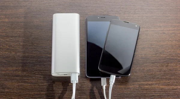 Power Bank charging two smartphones - dark wooden background