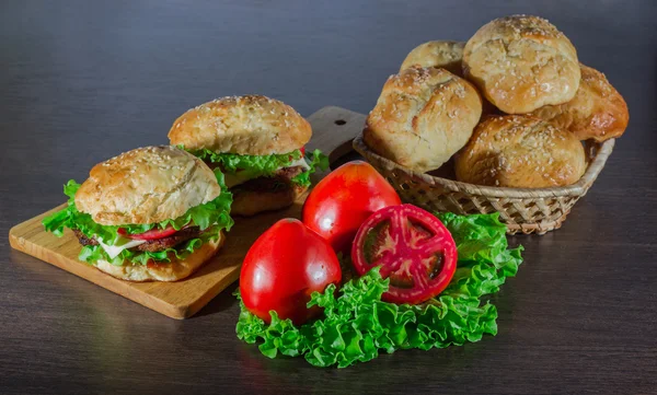 Sandwich - hamburger with burger, cheese, tomato, and onion on wooden background