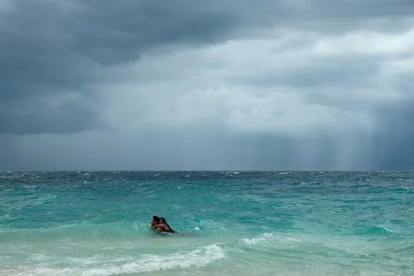 Moalboal. Cebu. Philippines - 06 aug 2016: Philippine young couple swimming in stormy tropical sea under cloudy dramatic sky of coming storm between big waves